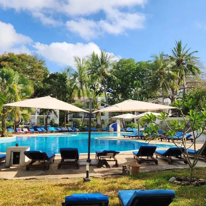 A sunlight poolside deck lined with comfortable lounge chairs and crisp white sun umbrellas.