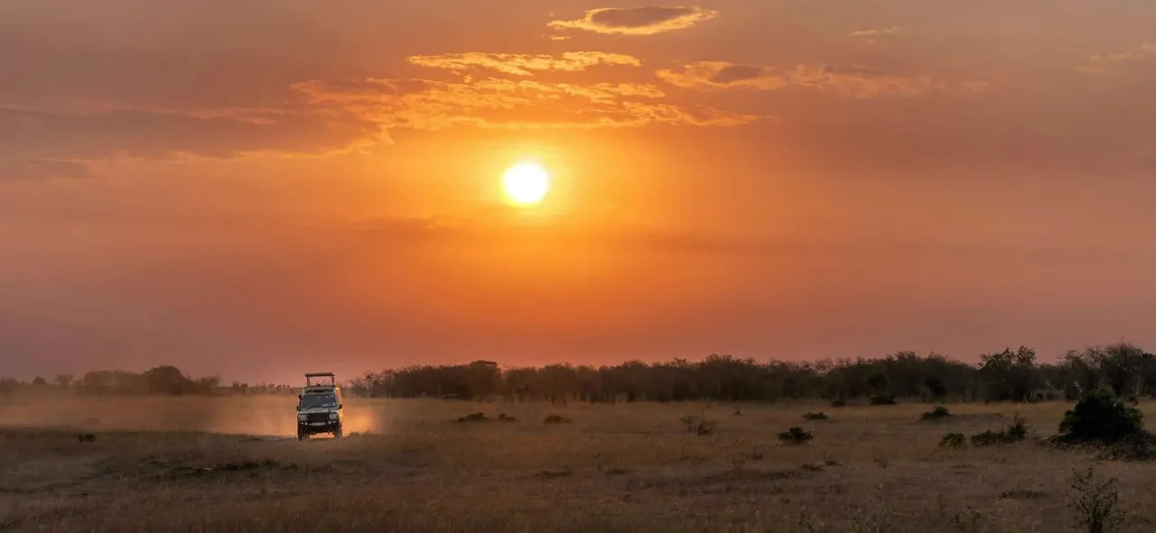 A safari vehicle on the Kenyan plains at sunset